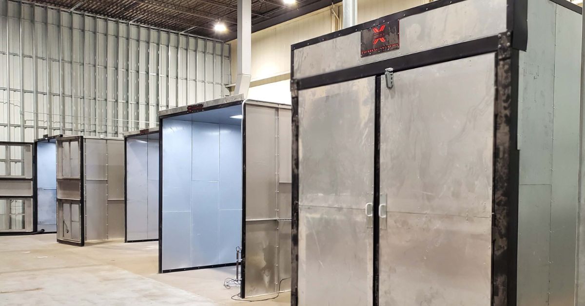 Powder-X industrial powder coating spray booths and curing ovens in a manufacturing facility.